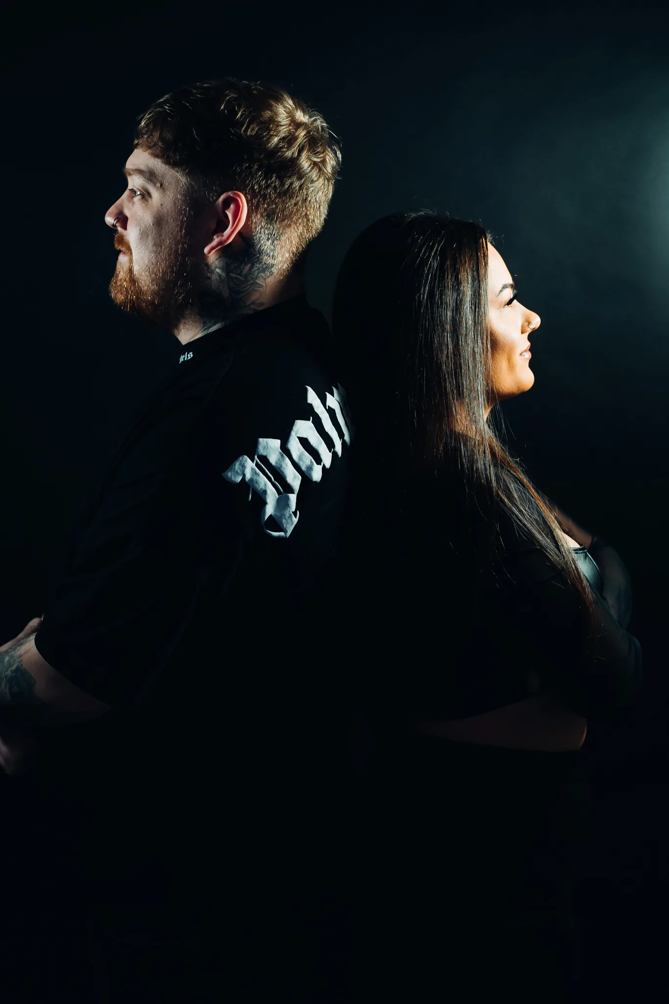 Jamie & Britney of Moodswing standing back to back in a blue-lit studio portrait