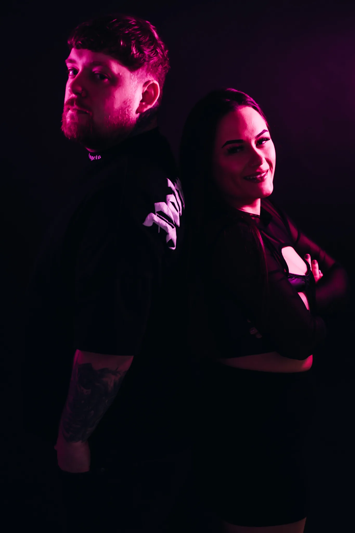 Jamie & Britney of Moodswing facing the camera in a magenta-lit studio portrait